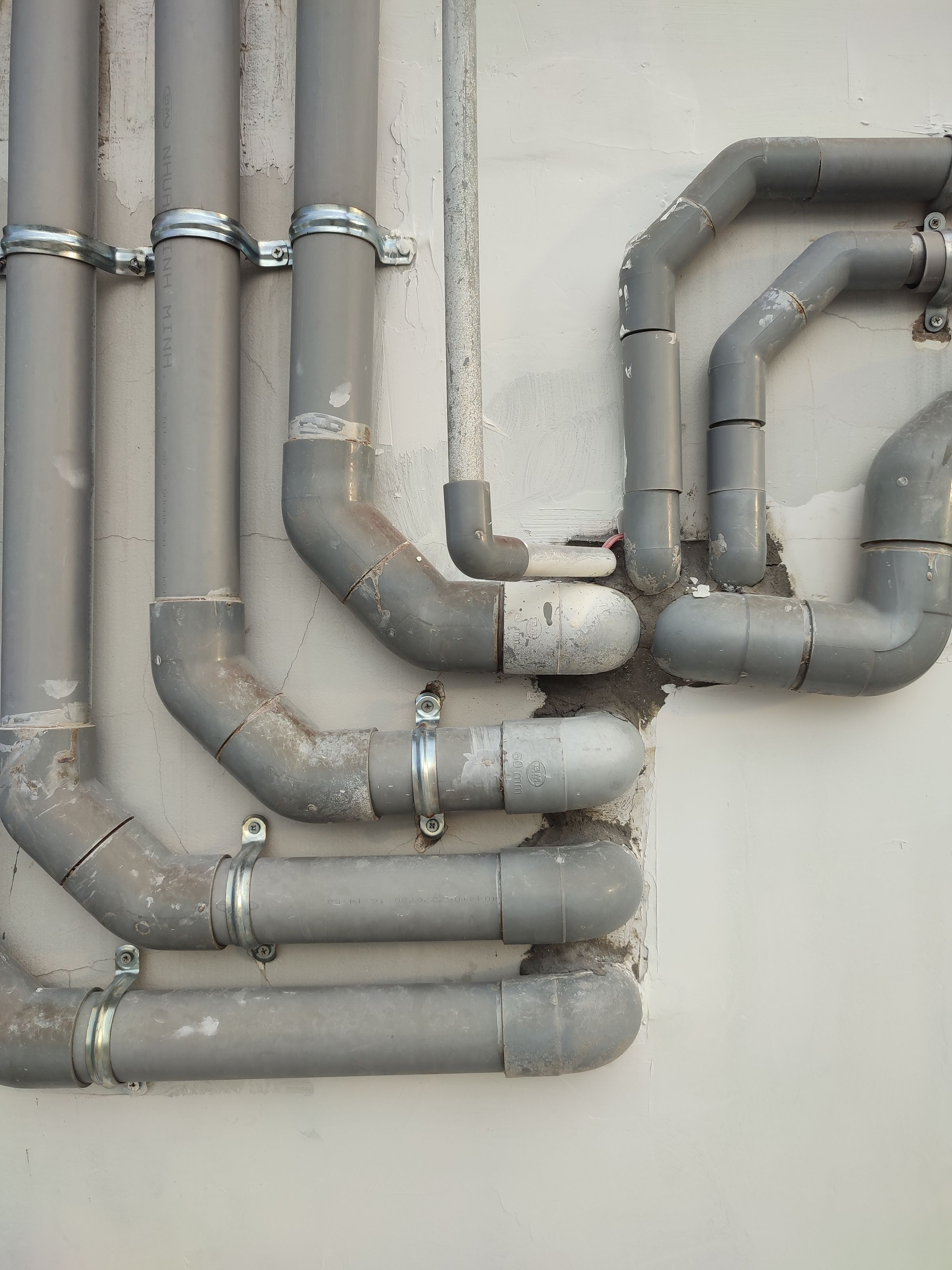 Interconnected gray metal pipes on an outdoor wall
