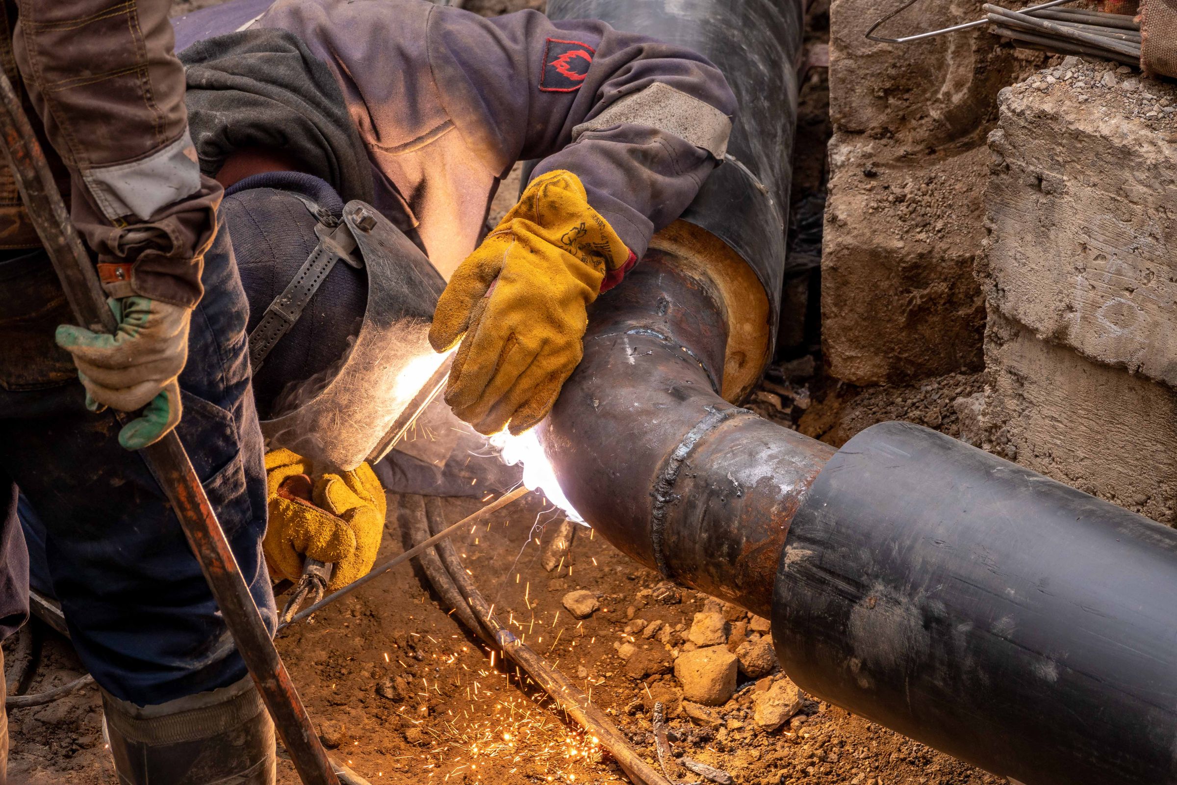 Worker welding steel pipes with safety gear